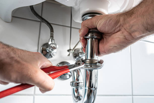 man repairing sink trap with adjustable pipe wrench in bathroom